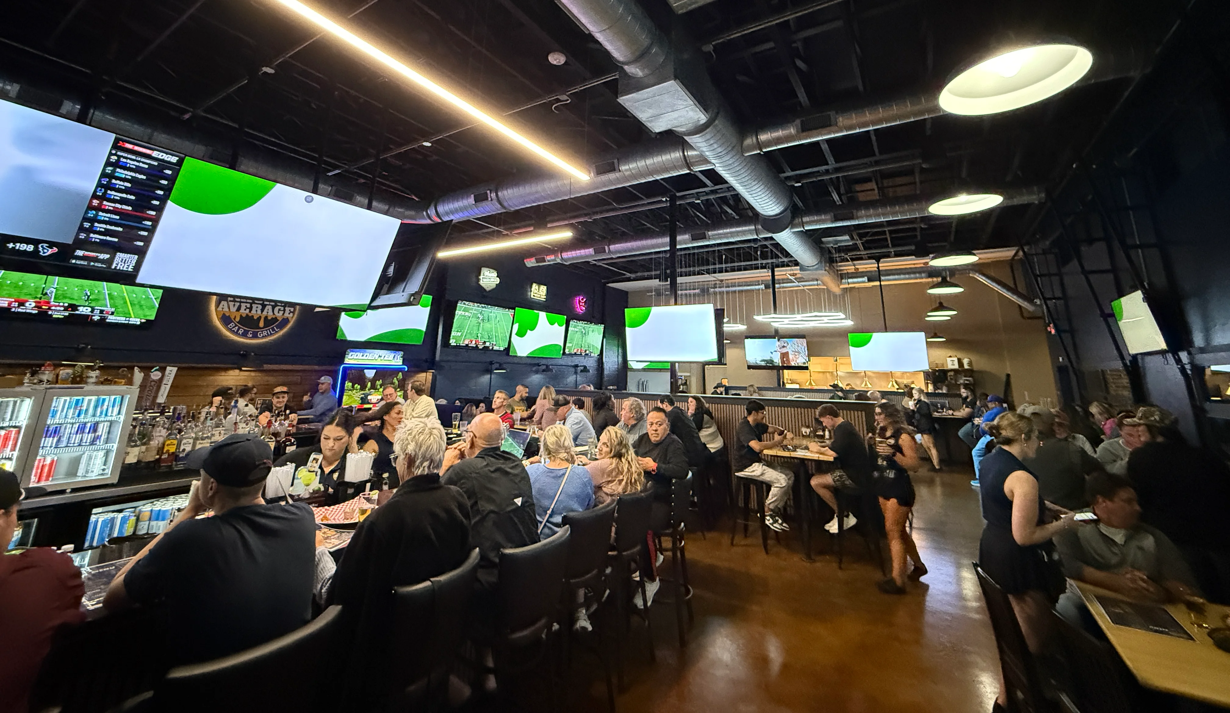 Lively sports bar interior with large screens and patrons enjoying drinks