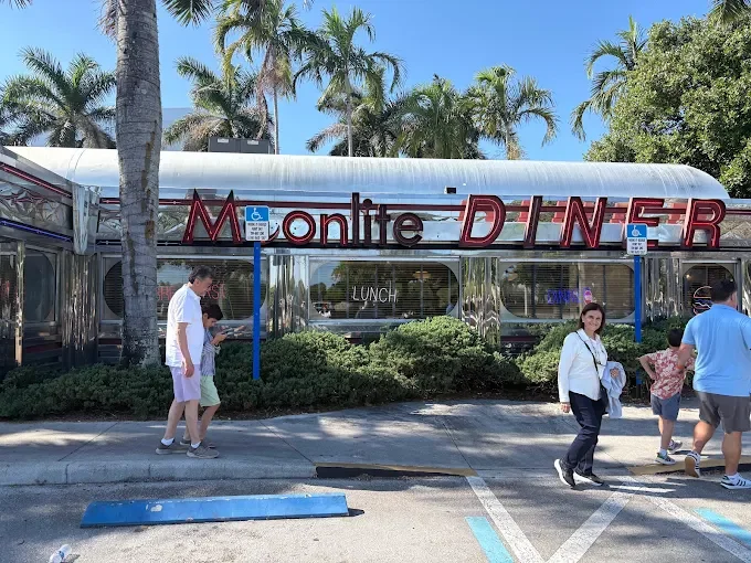 Front entrance of Moonlite Diner welcoming guests to a classic retro American diner surrounded by palm trees in South Florida.
