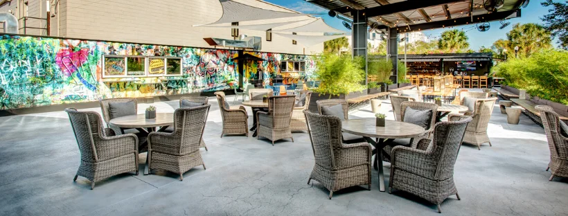Outdoor dining area with stylish wicker furniture and vibrant mural