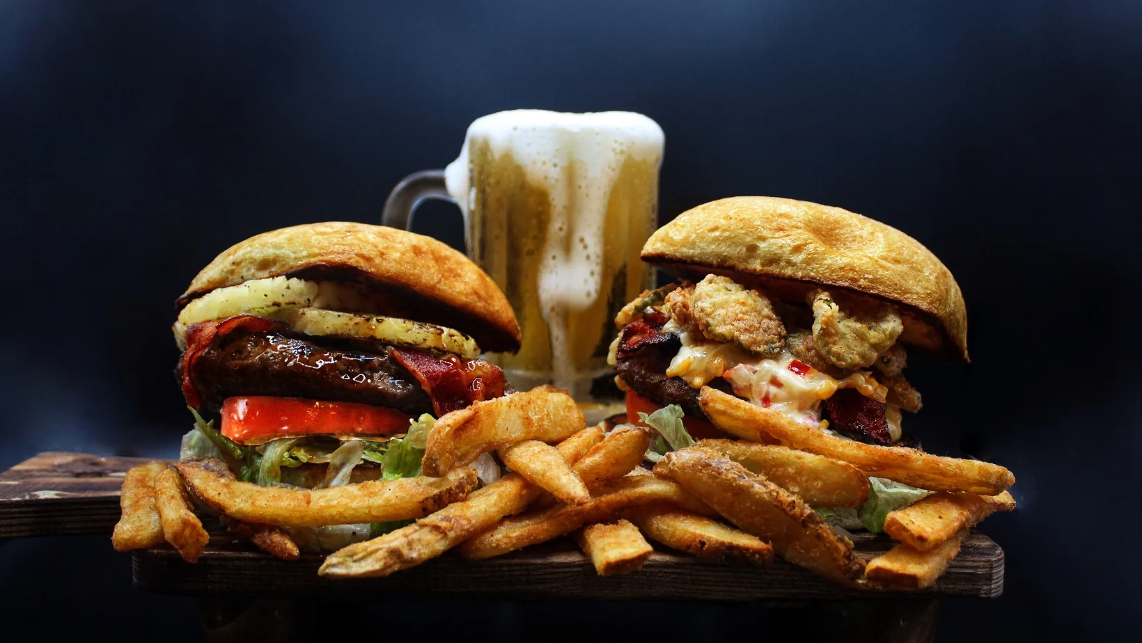 Gourmet burgers with fries and beer in a rustic setting