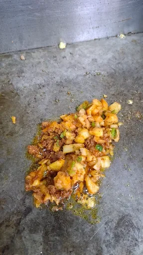 Sizzling chopped meat and vegetable stir-fry on a hot griddle