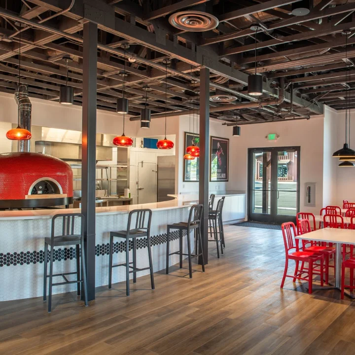 Modern restaurant interior with red accents and wood-fired oven