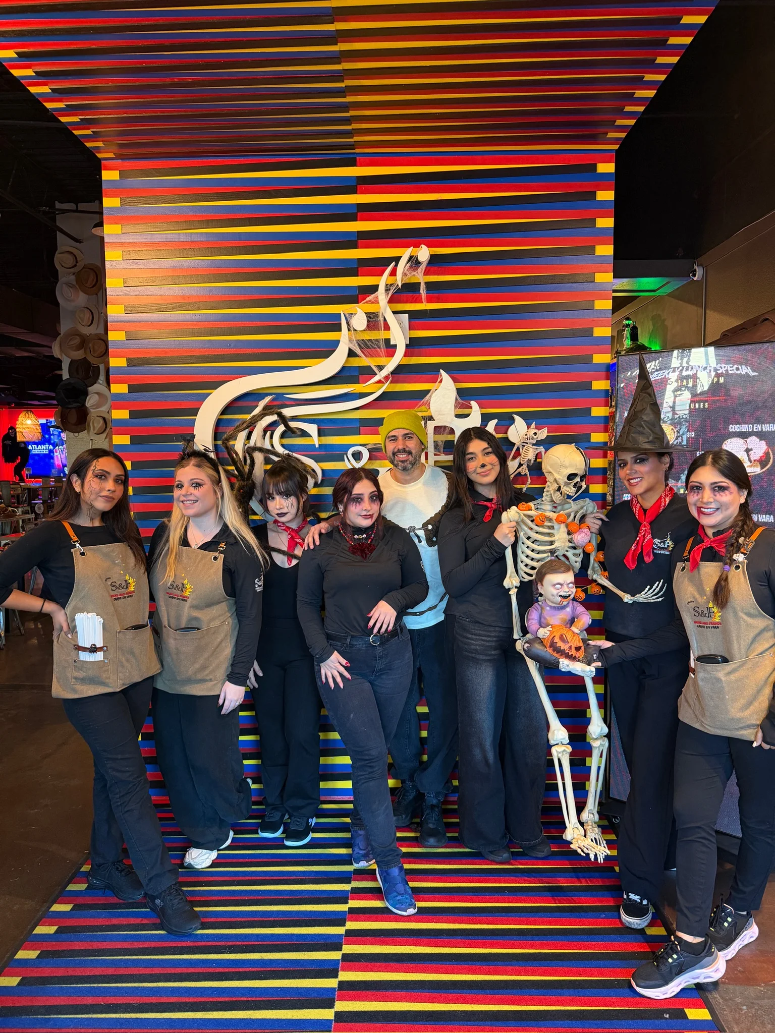 Staff posing in a vibrant restaurant with Halloween decorations