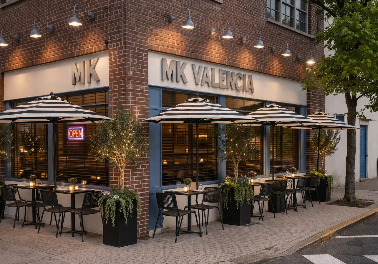 Outdoor dining area of MK Valencia with striped umbrellas and open sign.