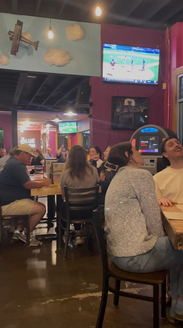 Interior of a lively restaurant with patrons enjoying food and drinks.