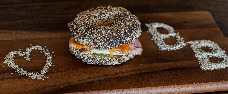 Bagel sandwich with ham and cheese on a wooden board