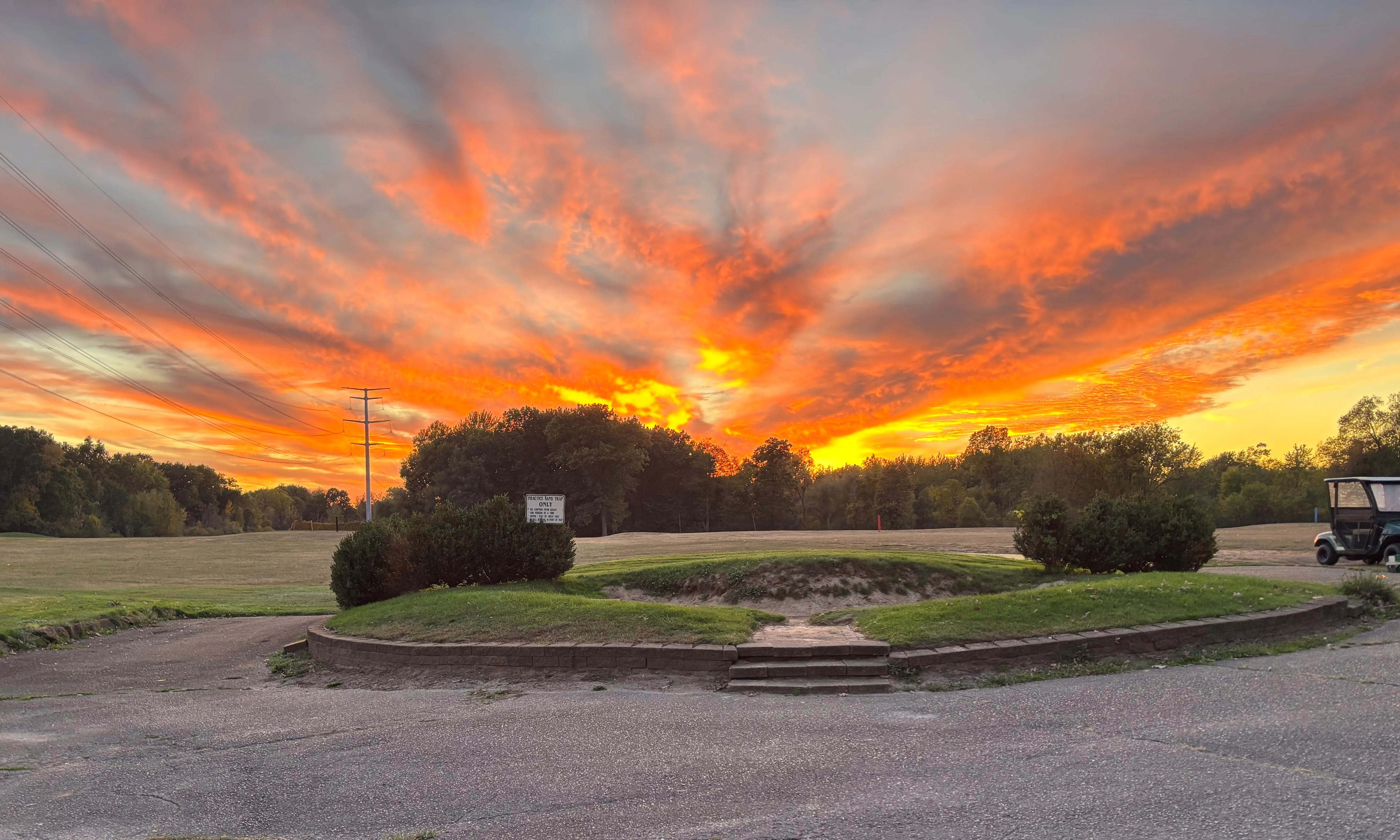 Vibrant sunset over a golf course with power lines