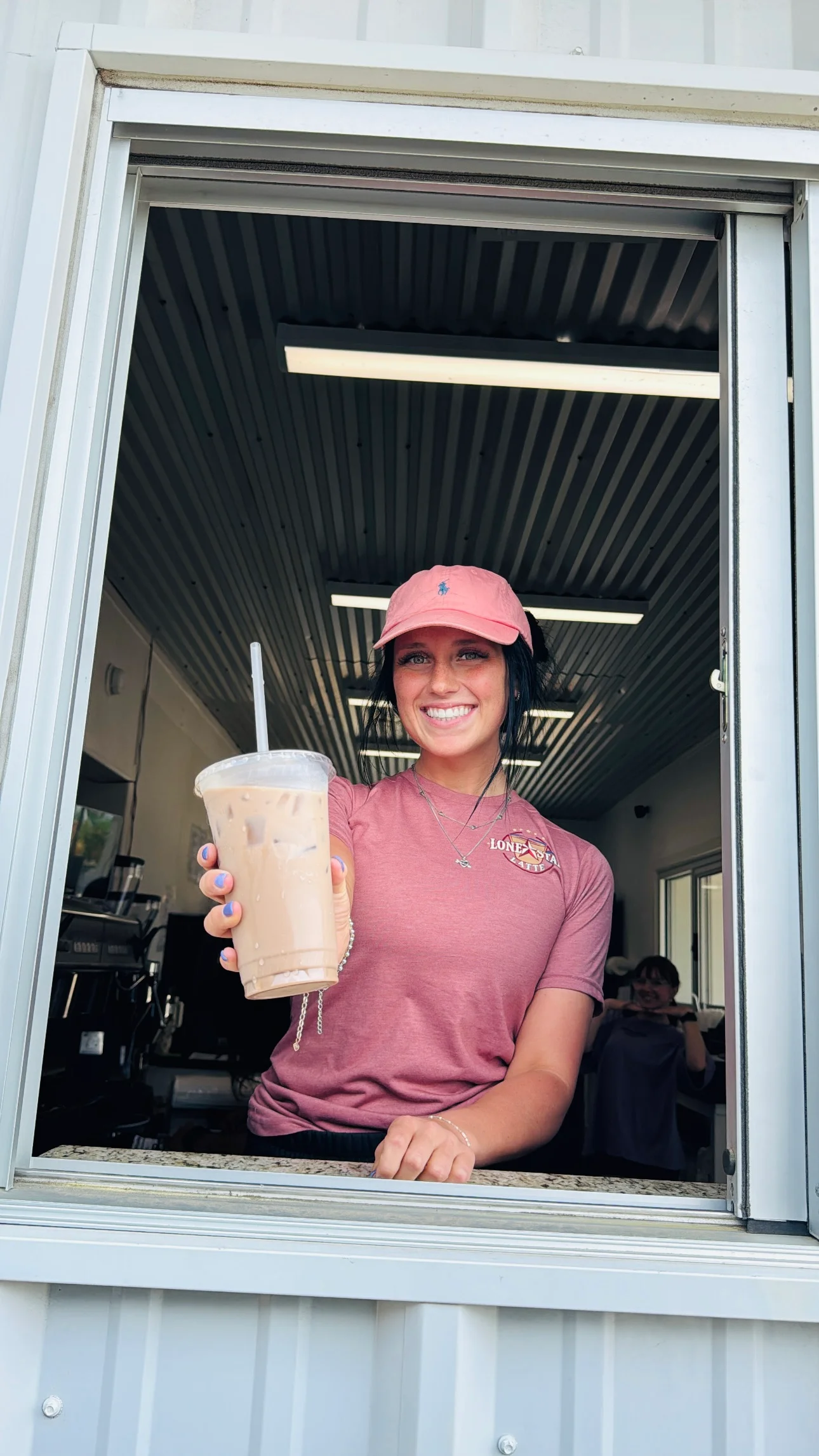 Barista serving iced coffee at a drive-thru window