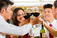 Friends toasting with red wine glasses in a festive restaurant setting
