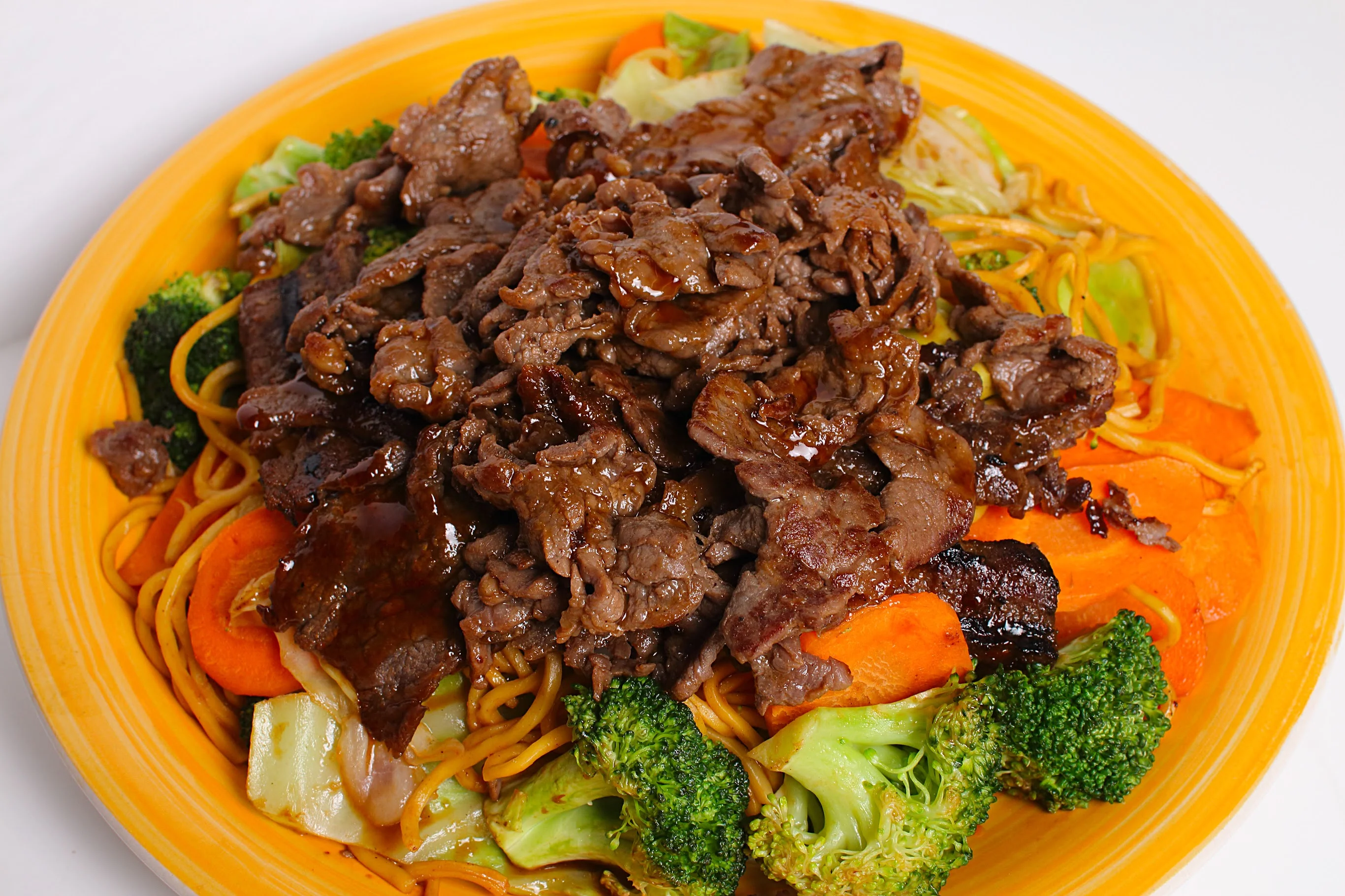 A large serving of stir-fried noodles, perfectly cooked and presented in a white bowl.