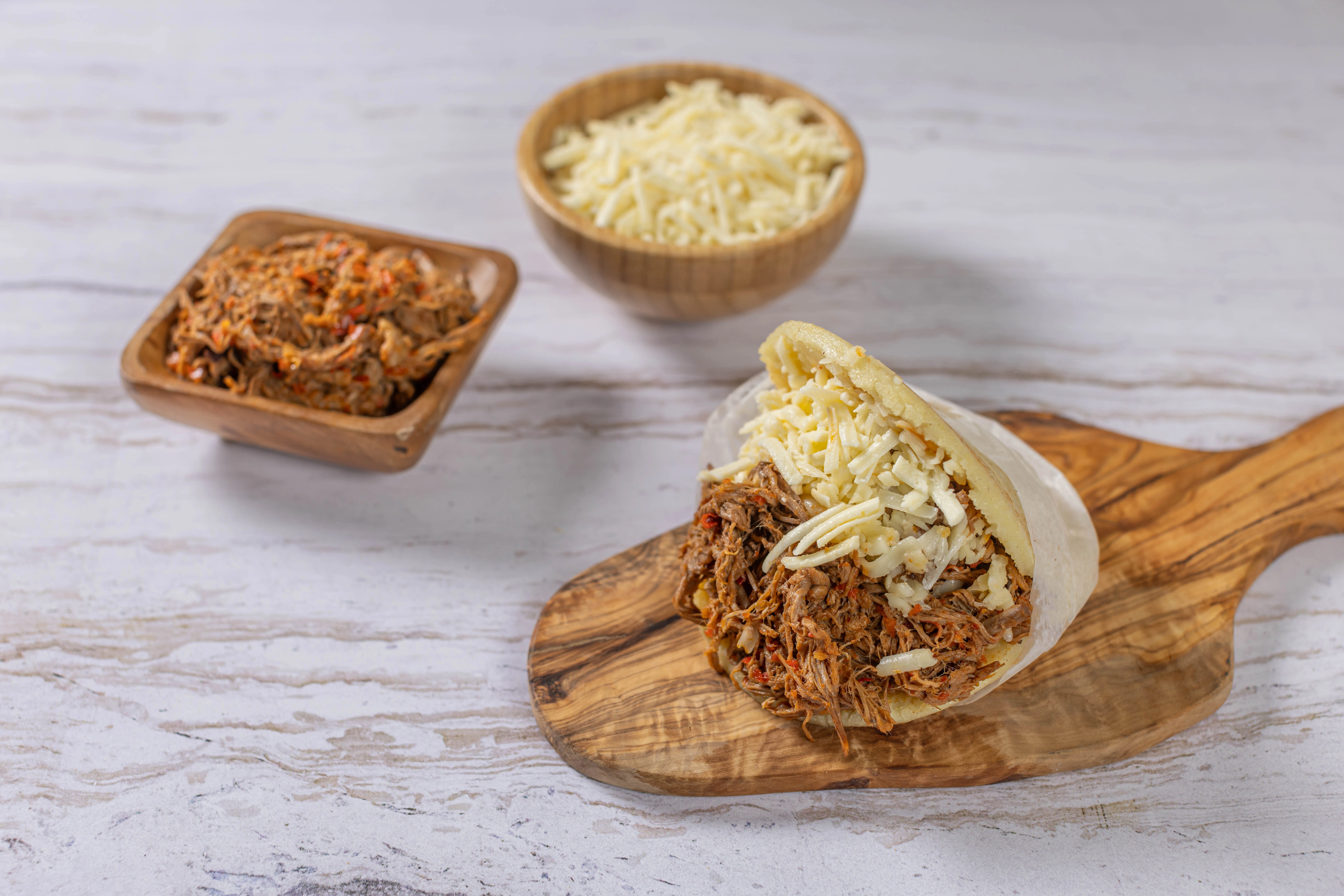 Freshly made arepas on a traditional budare (griddle), with one stuffed with juicy shredded beef and cheese at El Budare Cafe.