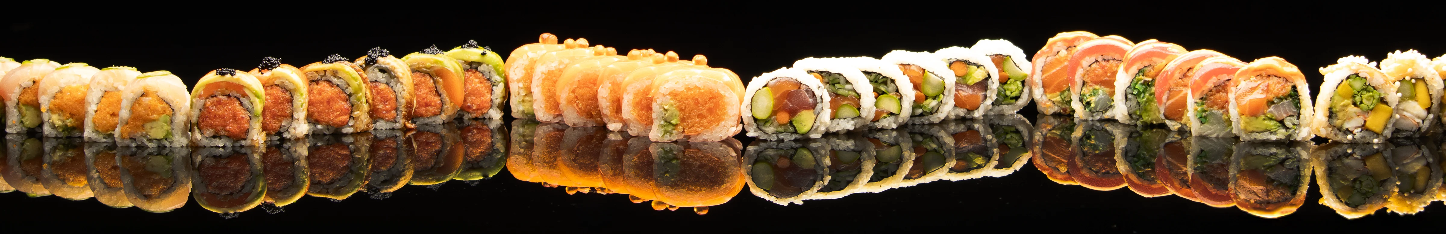 Assorted sushi rolls beautifully arranged on a reflective surface