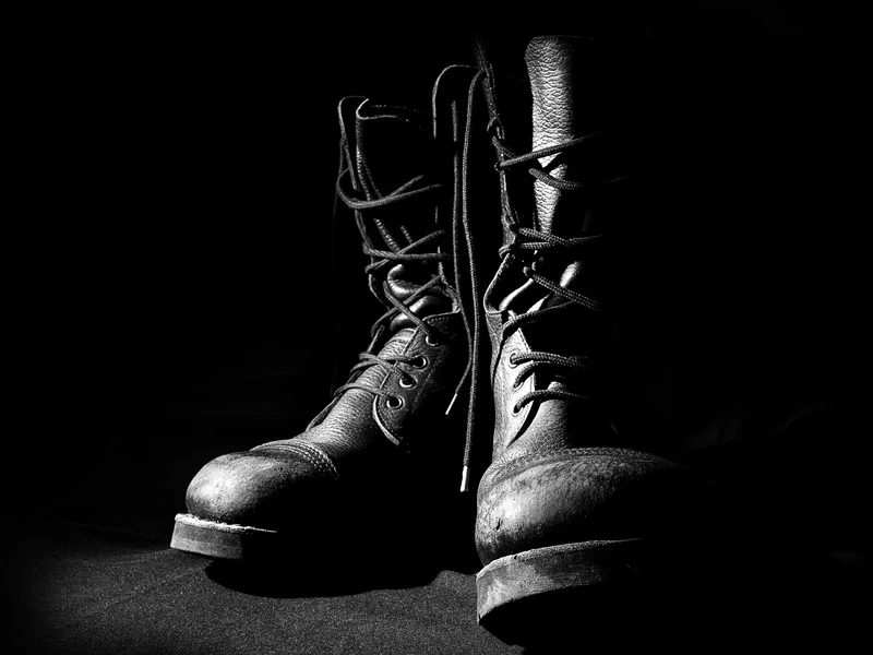 Black combat boots with laces in dramatic lighting