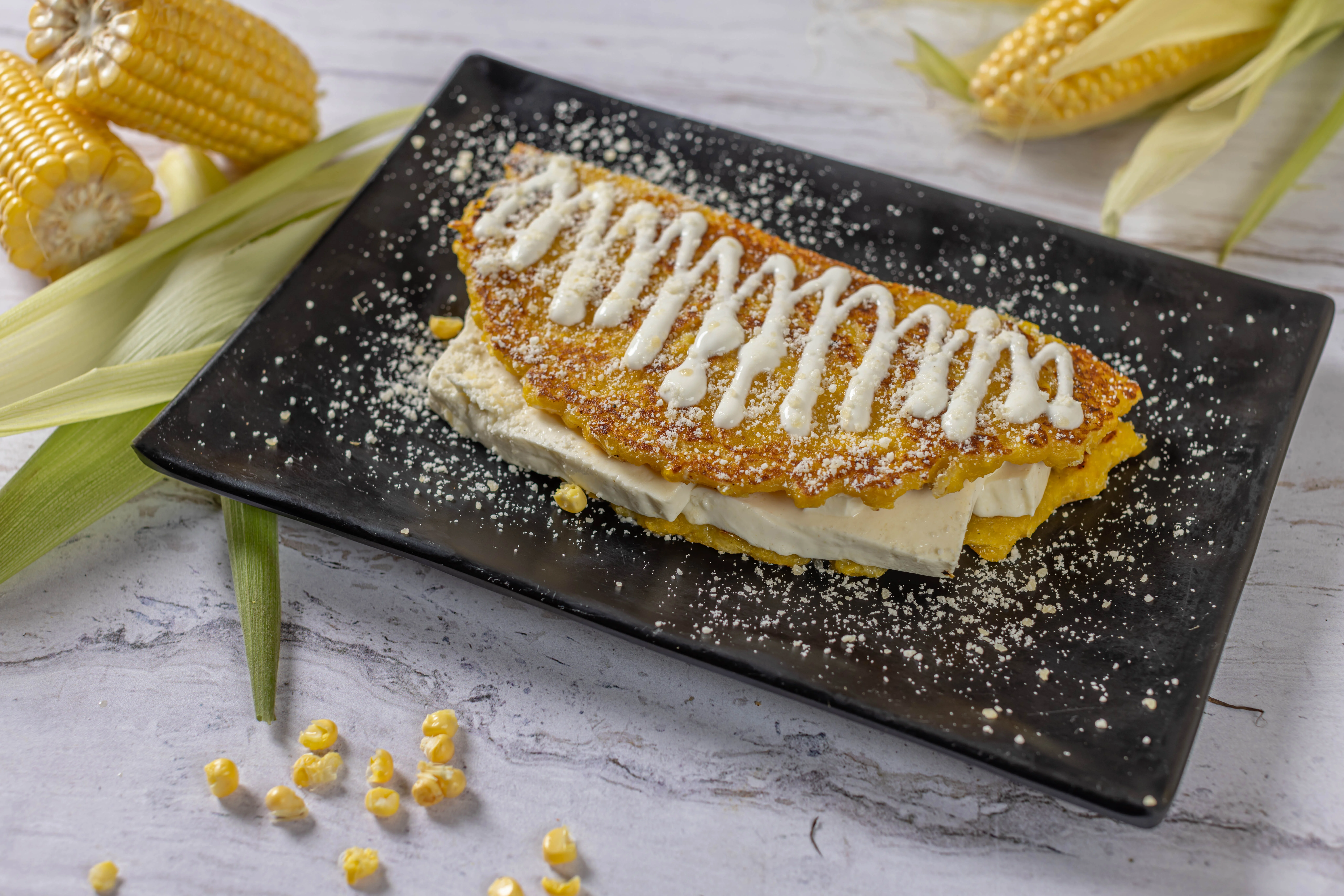 A traditional Venezuelan cachapa, which is a sweet corn pancake folded over a generous slice of soft white cheese and drizzled with cream.