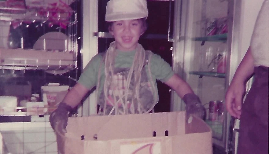 Child holding a large cardboard box in a restaurant setting