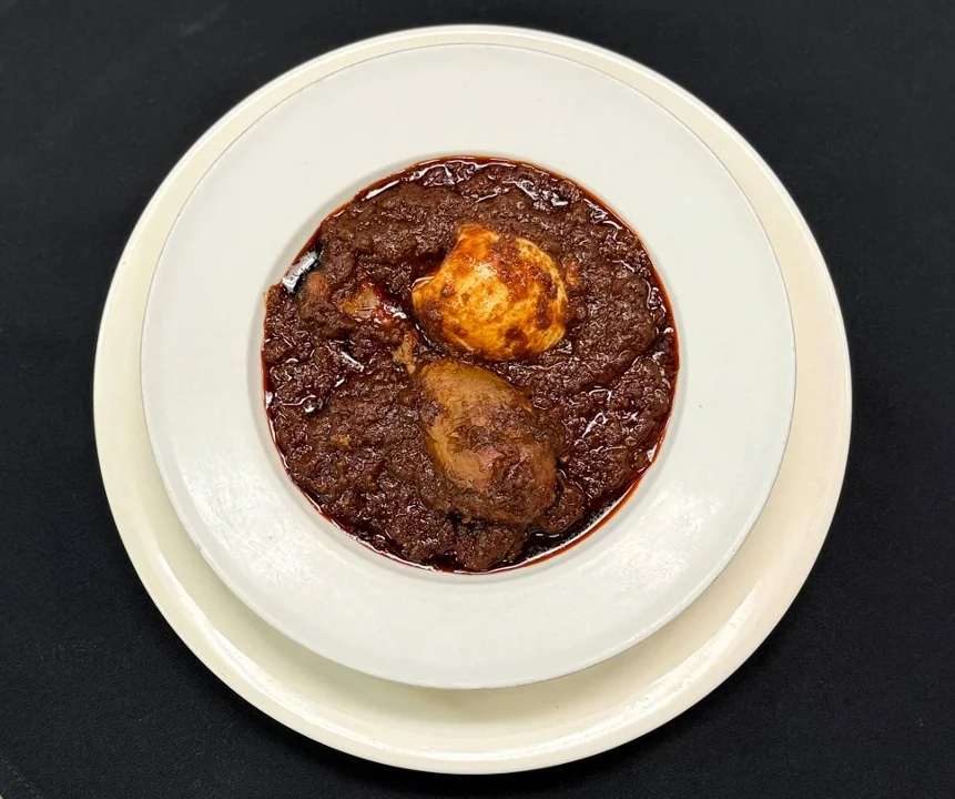 Rich and savory stew featuring boiled eggs and tender meat, served in a deep white bowl.