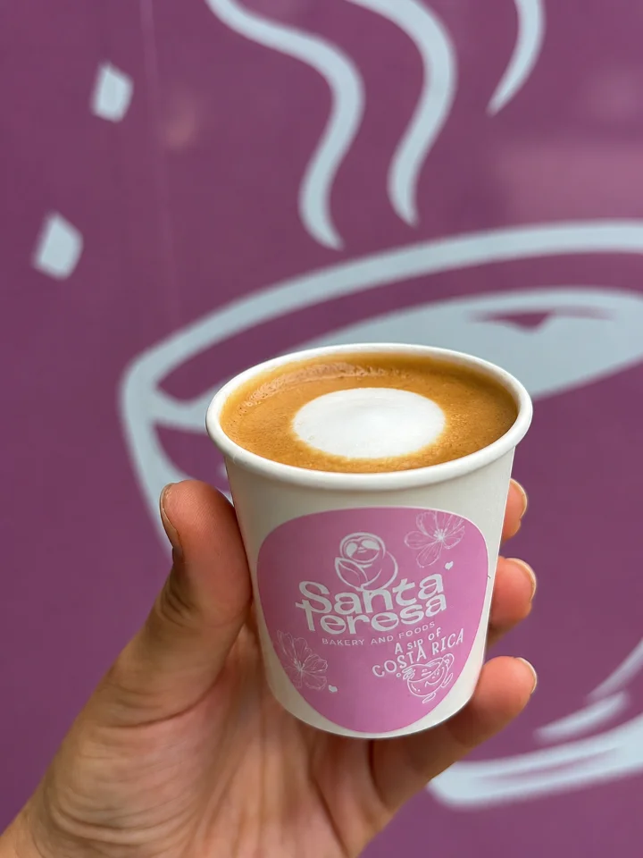 A small cup of macchiato with a creamy froth on top, showcased against a colorful purple background.