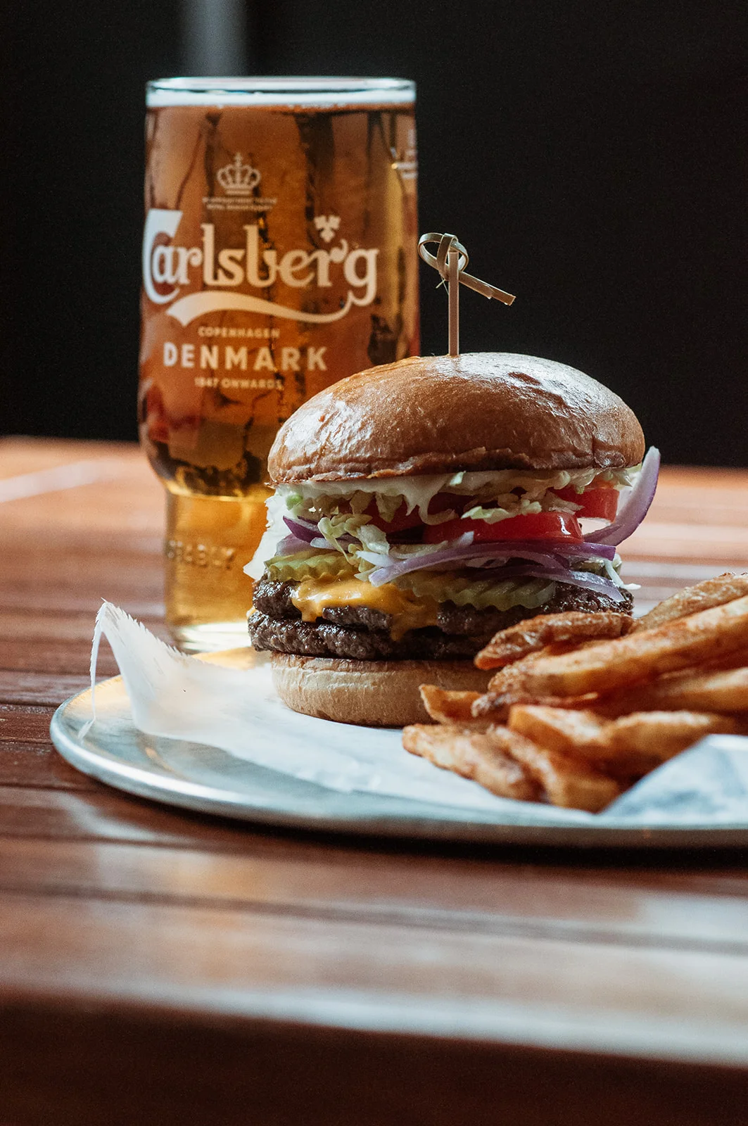 Juicy cheeseburger with fries and a cold beer in a casual dining setting