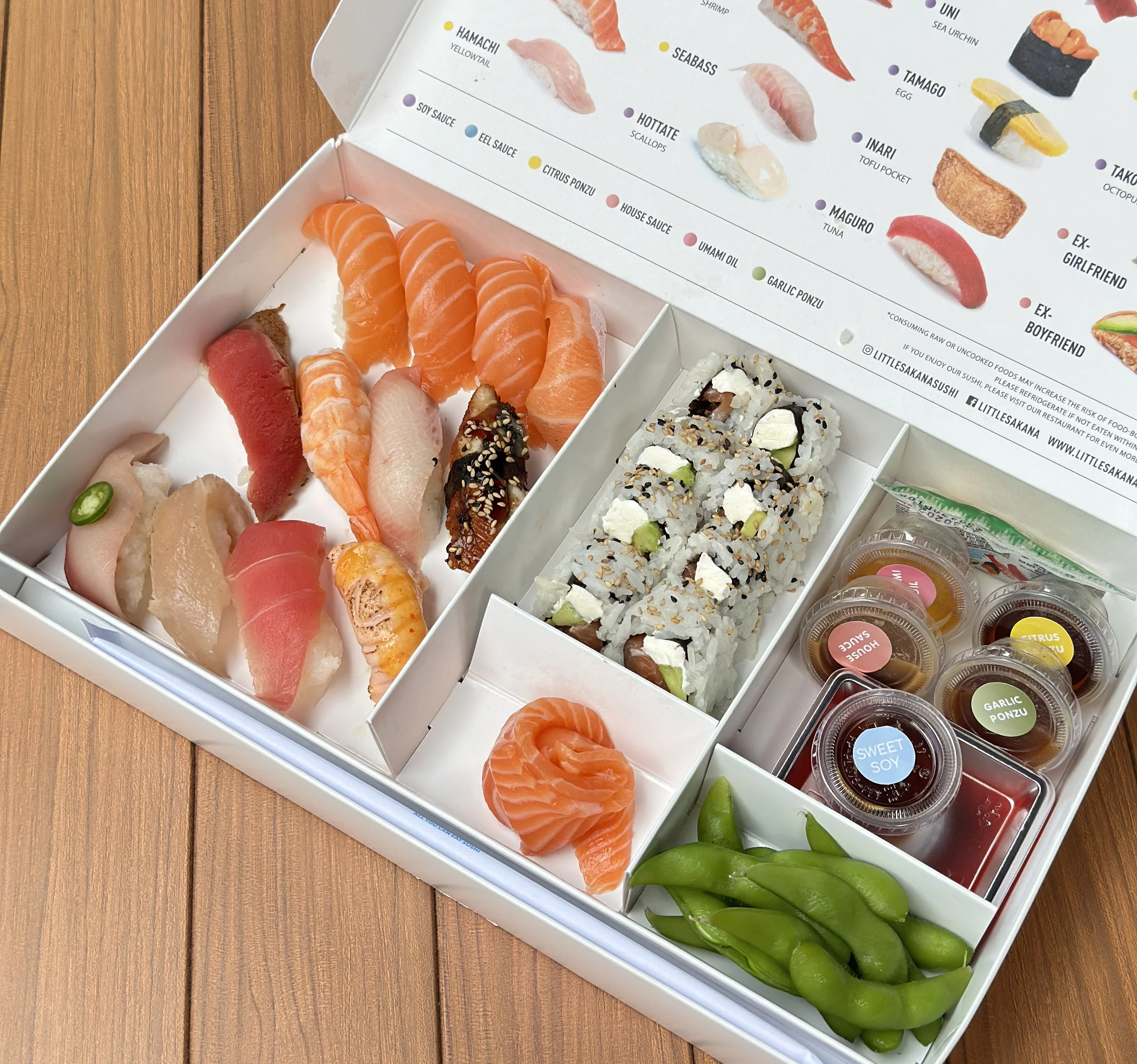 Assorted sushi platter with sashimi and rolls in a takeout box