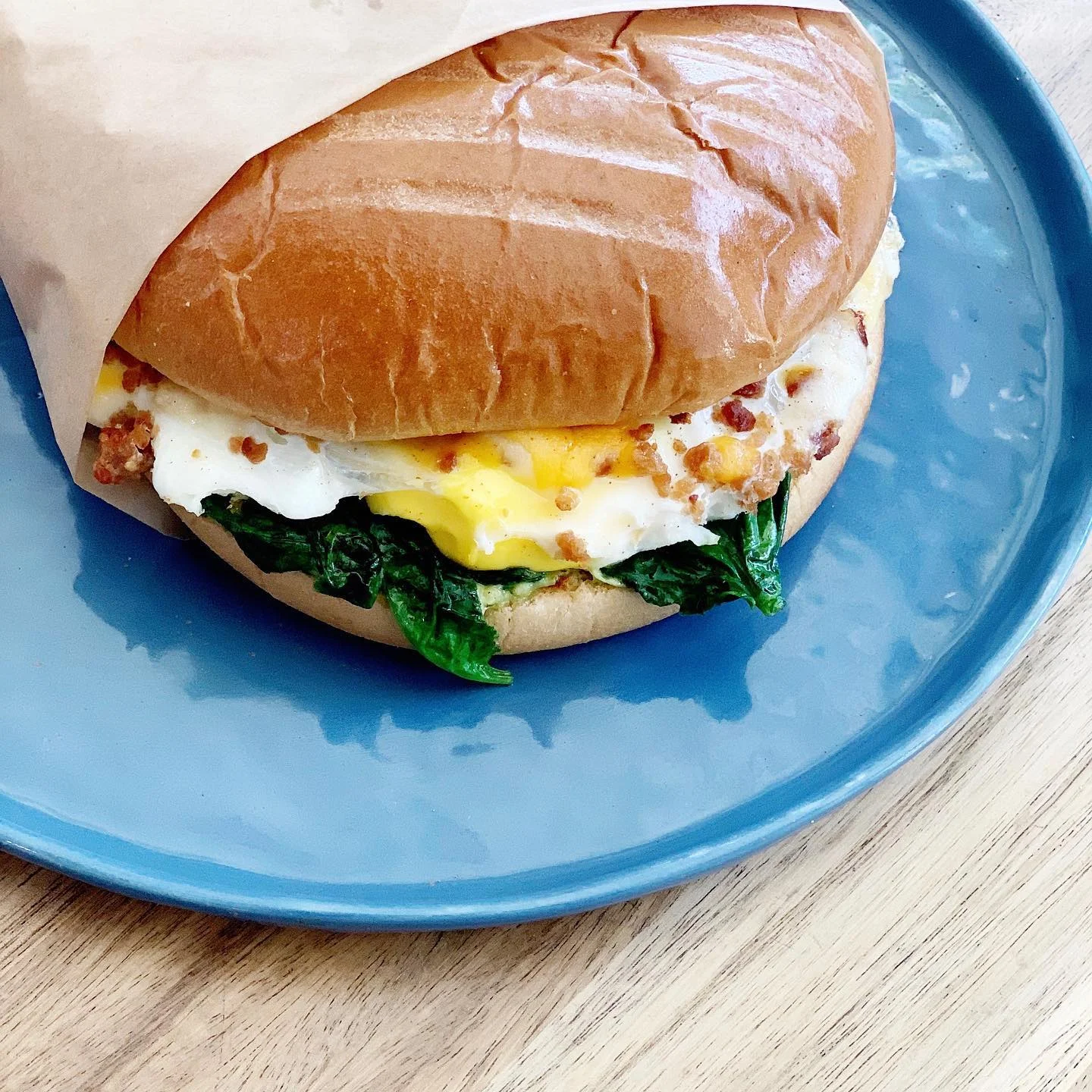 Try our new breakfast sandwich! Soft brioche bread stuffed with an over easy egg, bacon, cheese, sautéed spinach and aioli spread!