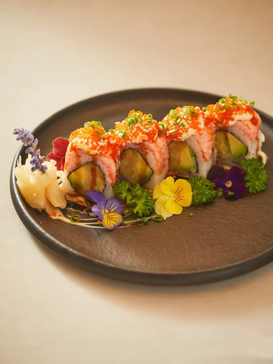 Japanese sushi rolls garnished with flowers and sauces