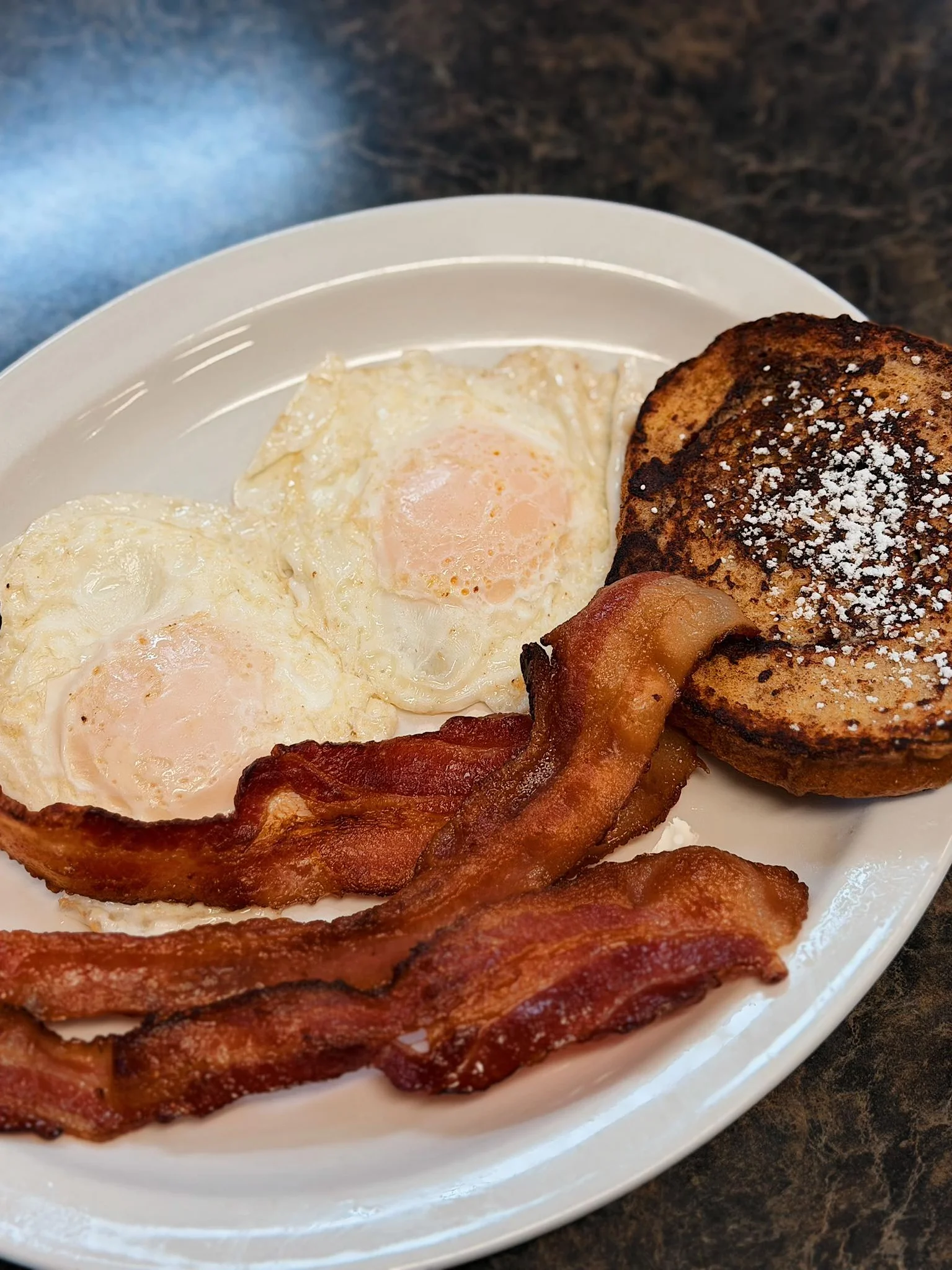 Classic American breakfast with eggs, bacon, and French toast