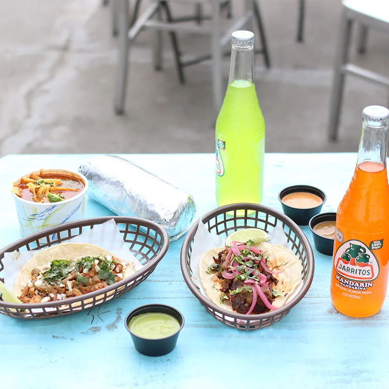 Authentic Mexican tacos with salsa and Jarritos sodas on a blue table