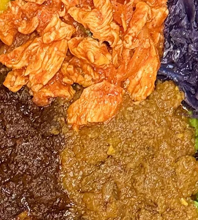 Another variation of an Ethiopian platter, showcasing a mix of meats and vegetables served on a base of injera. The assortment of dishes presents a variety of textures and flavors.