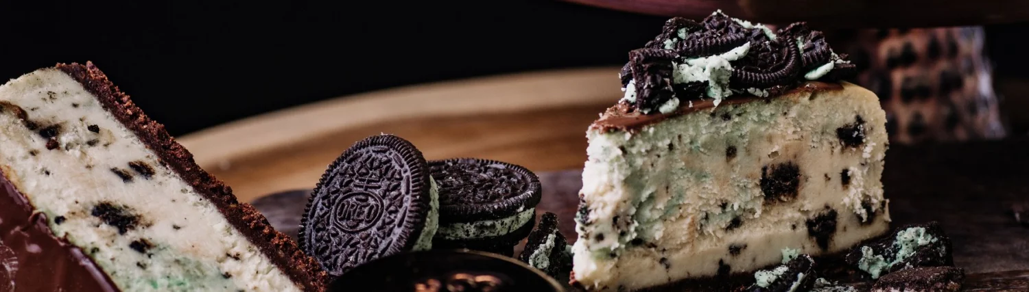 Delicious mint chocolate cheesecake with Oreo cookies on a wooden platter.