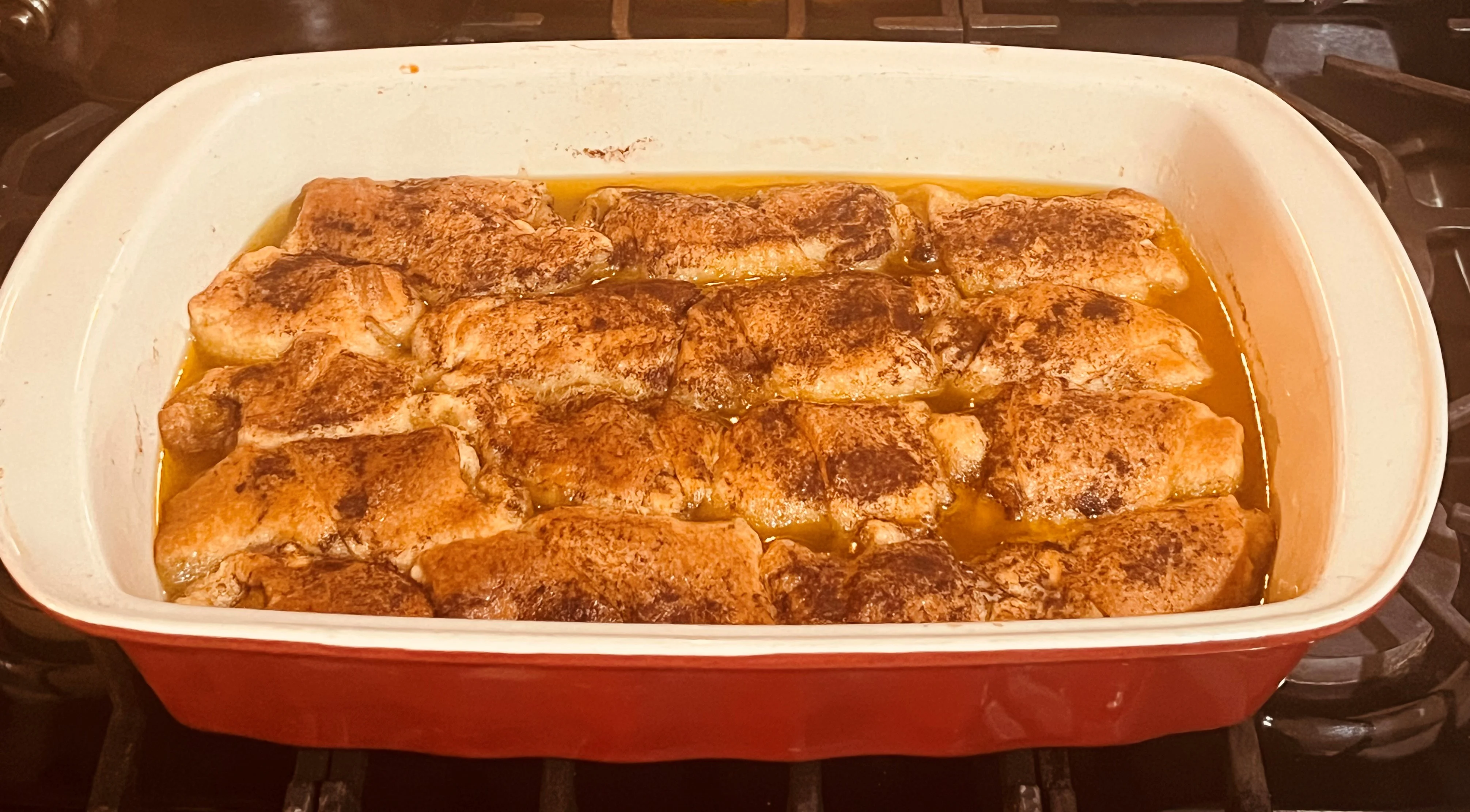 A baked dessert in a red dish, featuring a golden-brown topping and a soft filling underneath.