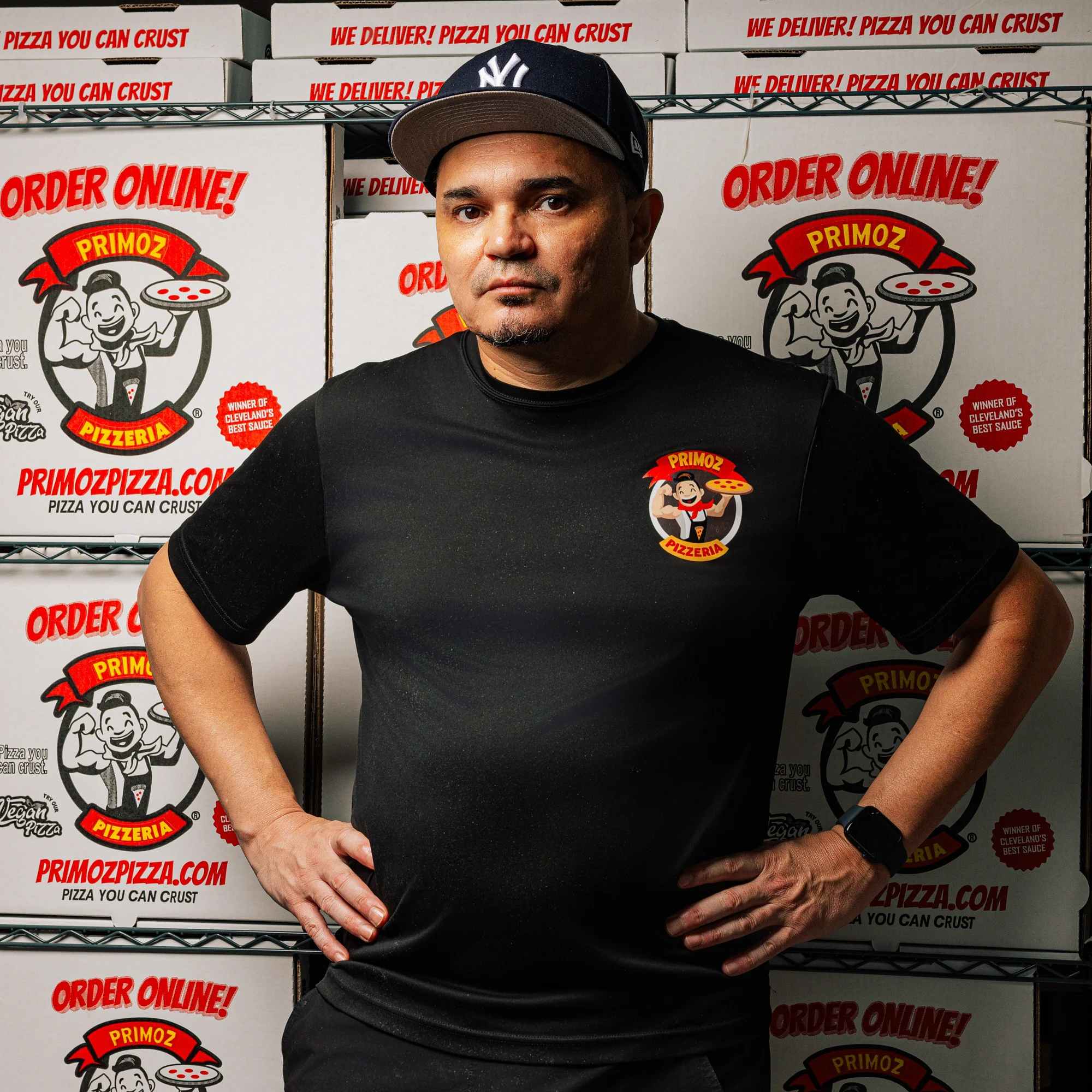 Owner of Primoz Pizzeria standing confidently in front of pizza boxes