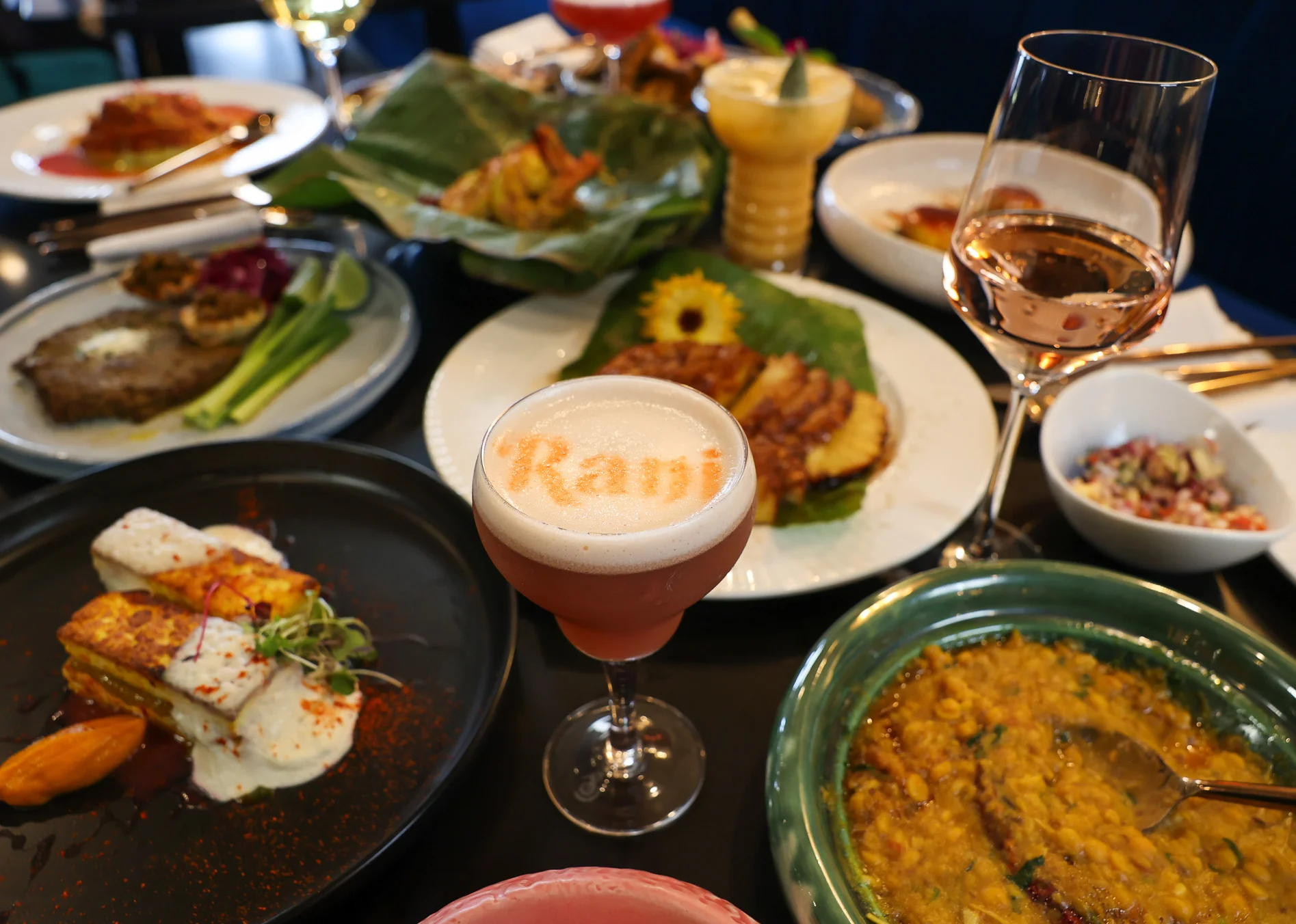 Colorful Indian thali with cocktails and diverse dishes