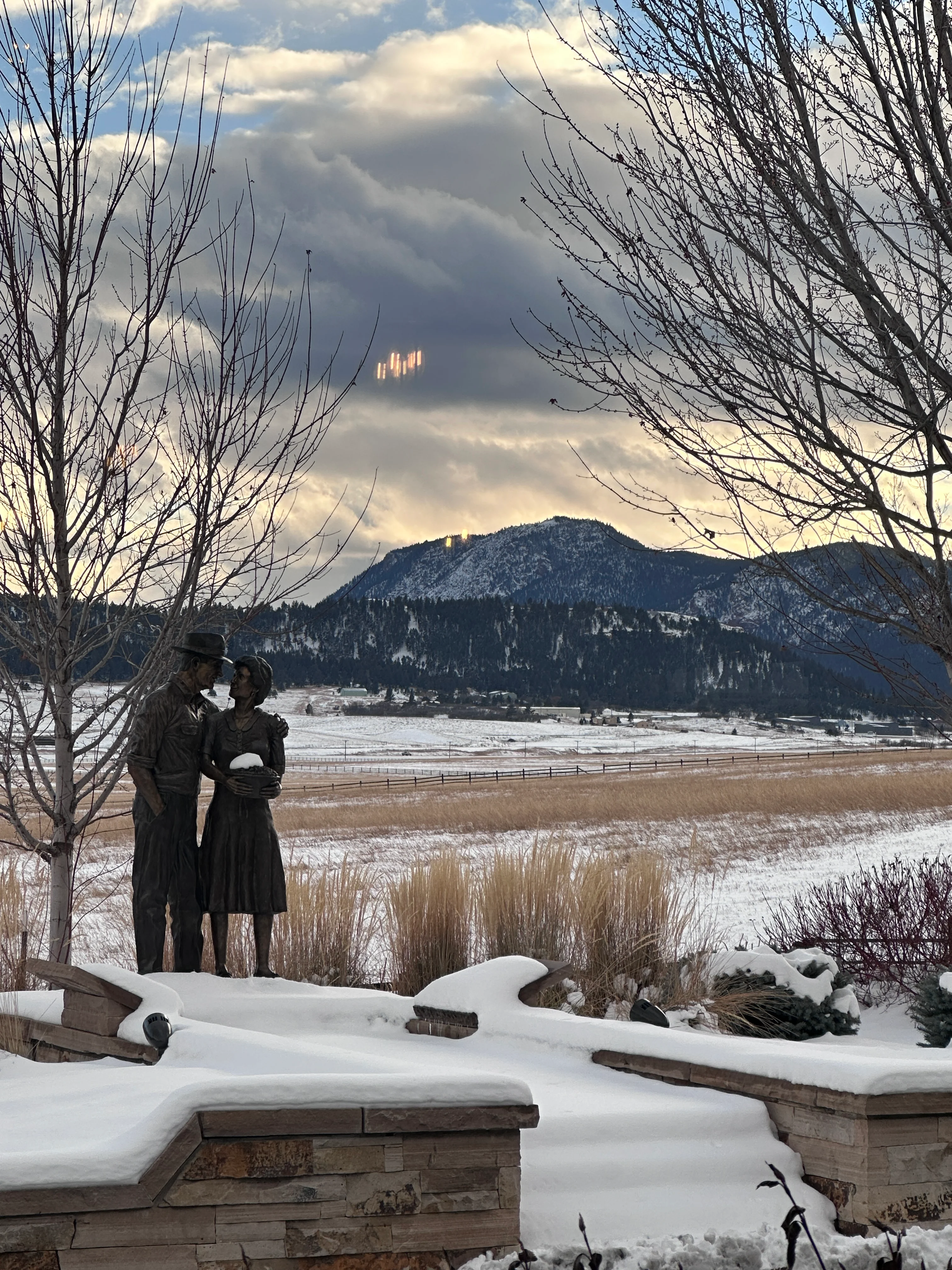 Bronze statue of a couple in a snowy landscape with mountains in the background