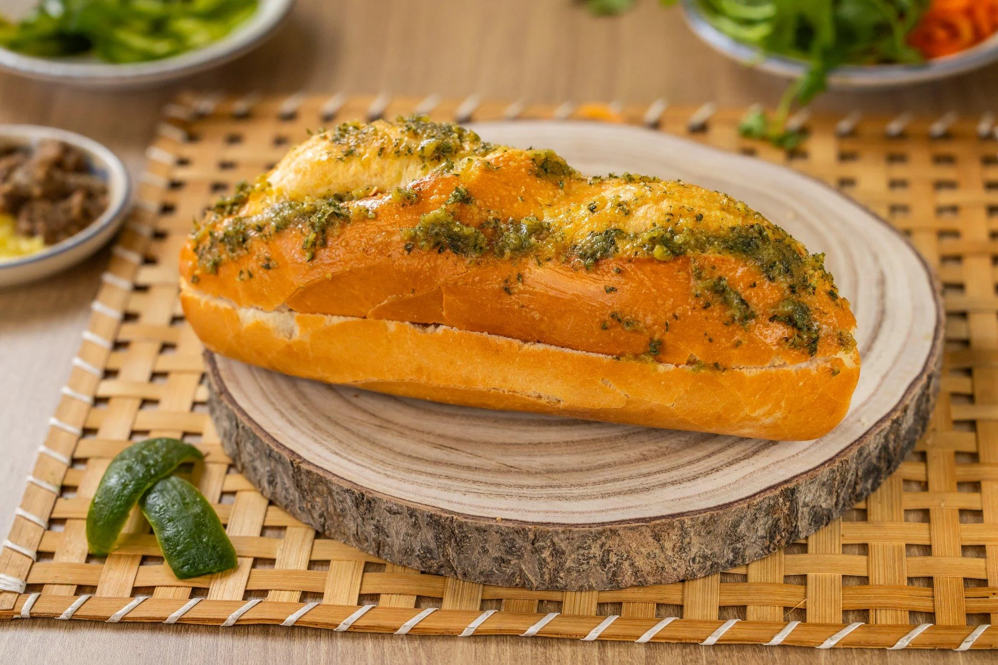 A loaf of garlic bread topped with herbs, resting on a wooden board.
