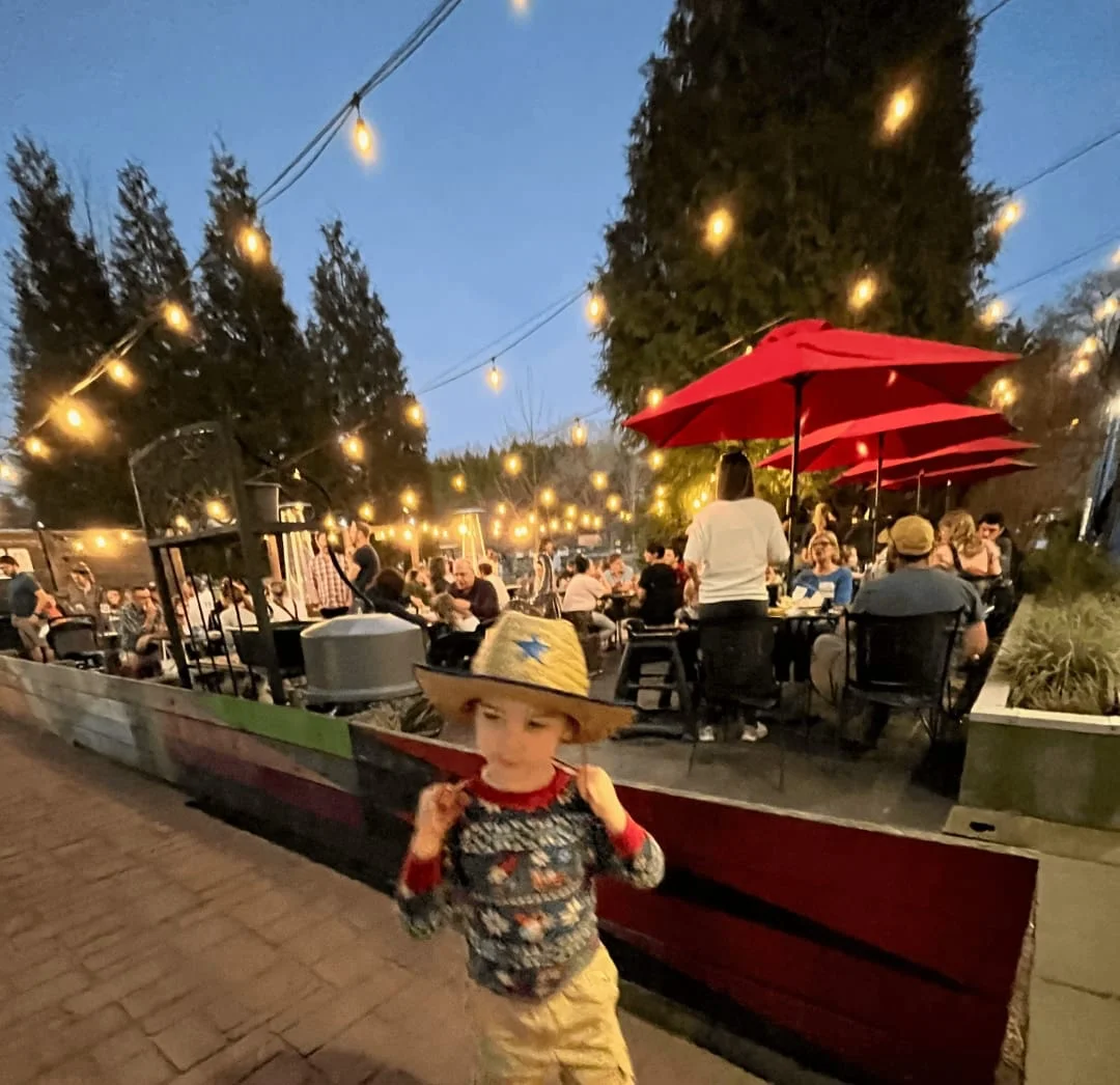 Outdoor dining area with string lights and red umbrellas