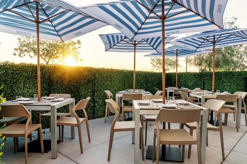 Outdoor dining area with striped umbrellas at sunset