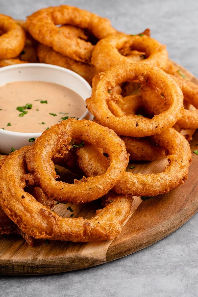 Close-up of vegan beer-battered crispy onion rings on a plate.