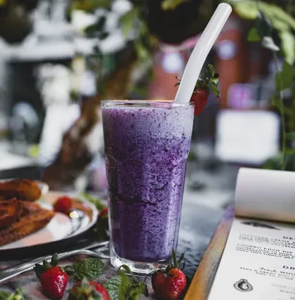 Purple ube shake with churros and strawberries on a rustic table