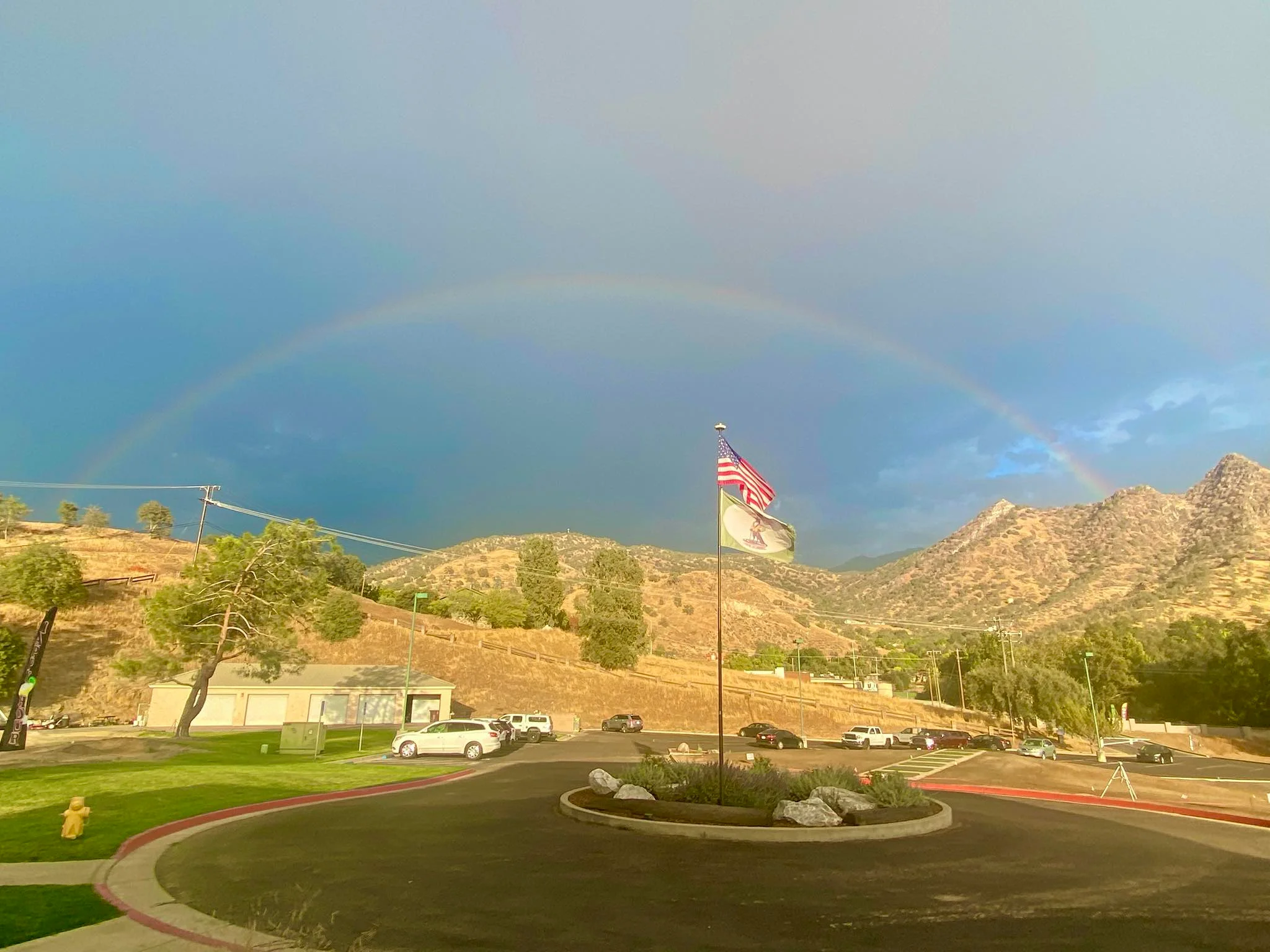 Scenic view of a rainbow over mountains with flags in the foreground