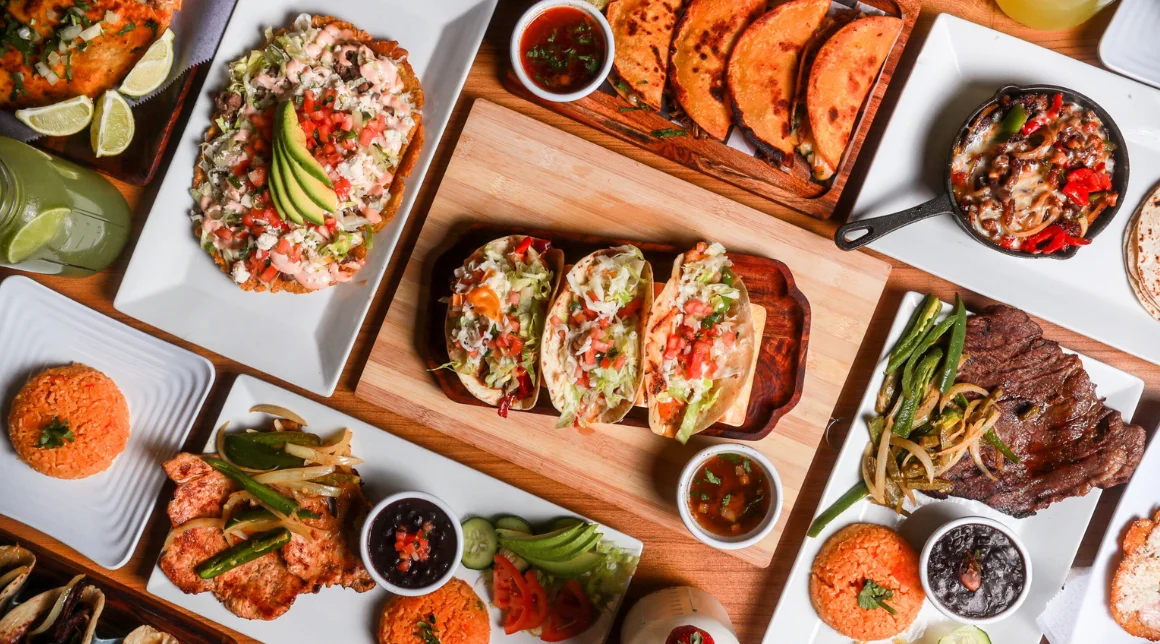 Assorted Mexican tacos with sides and sauces on a wooden platter