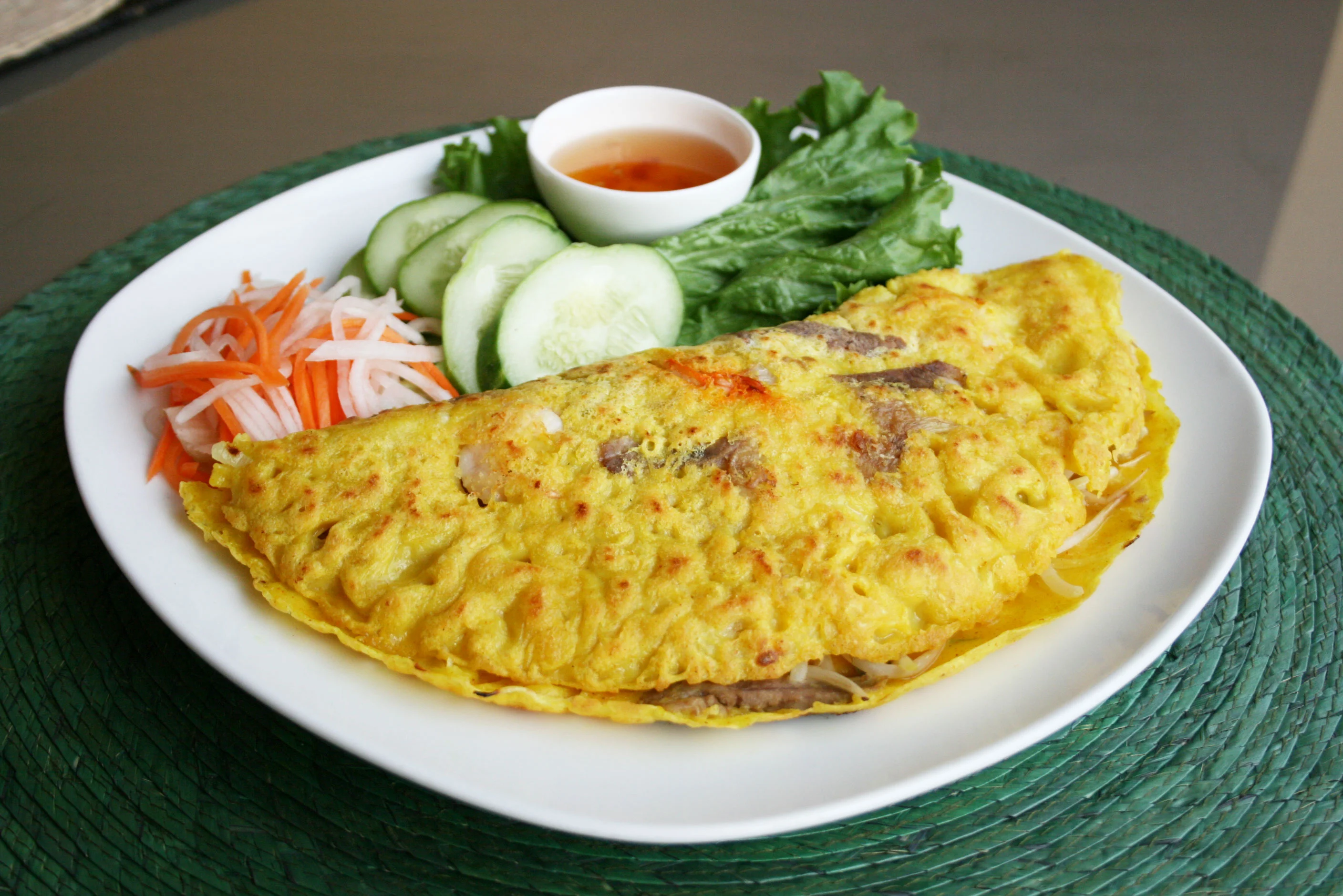Vietnamese banh xeo with fresh herbs and dipping sauce