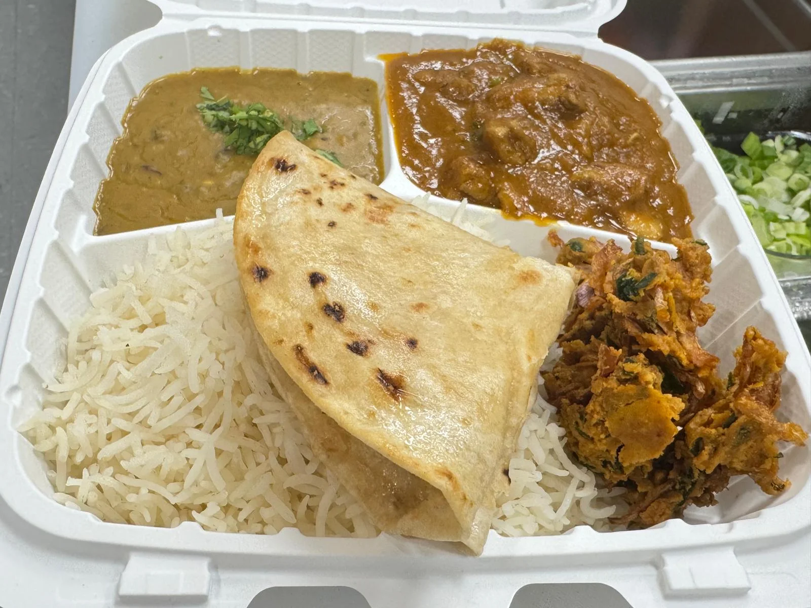 Indian thali with rice, naan, dal, curry, and vegetable fritters