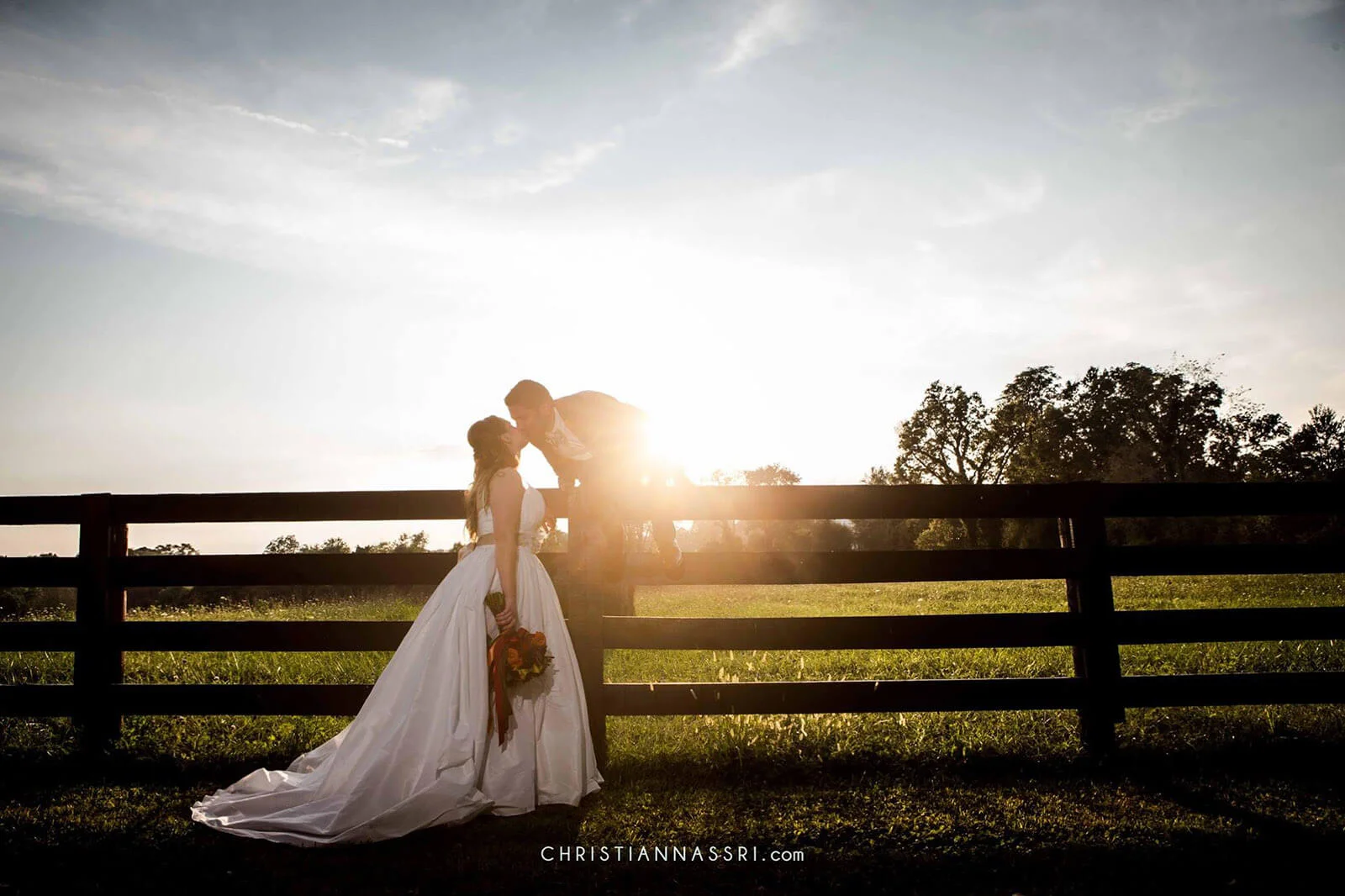 Couple sharing a kiss at sunset in a rustic outdoor setting