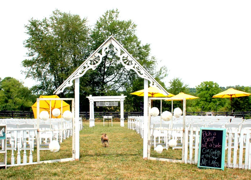 Outdoor wedding ceremony setup with white chairs and yellow umbrellas
