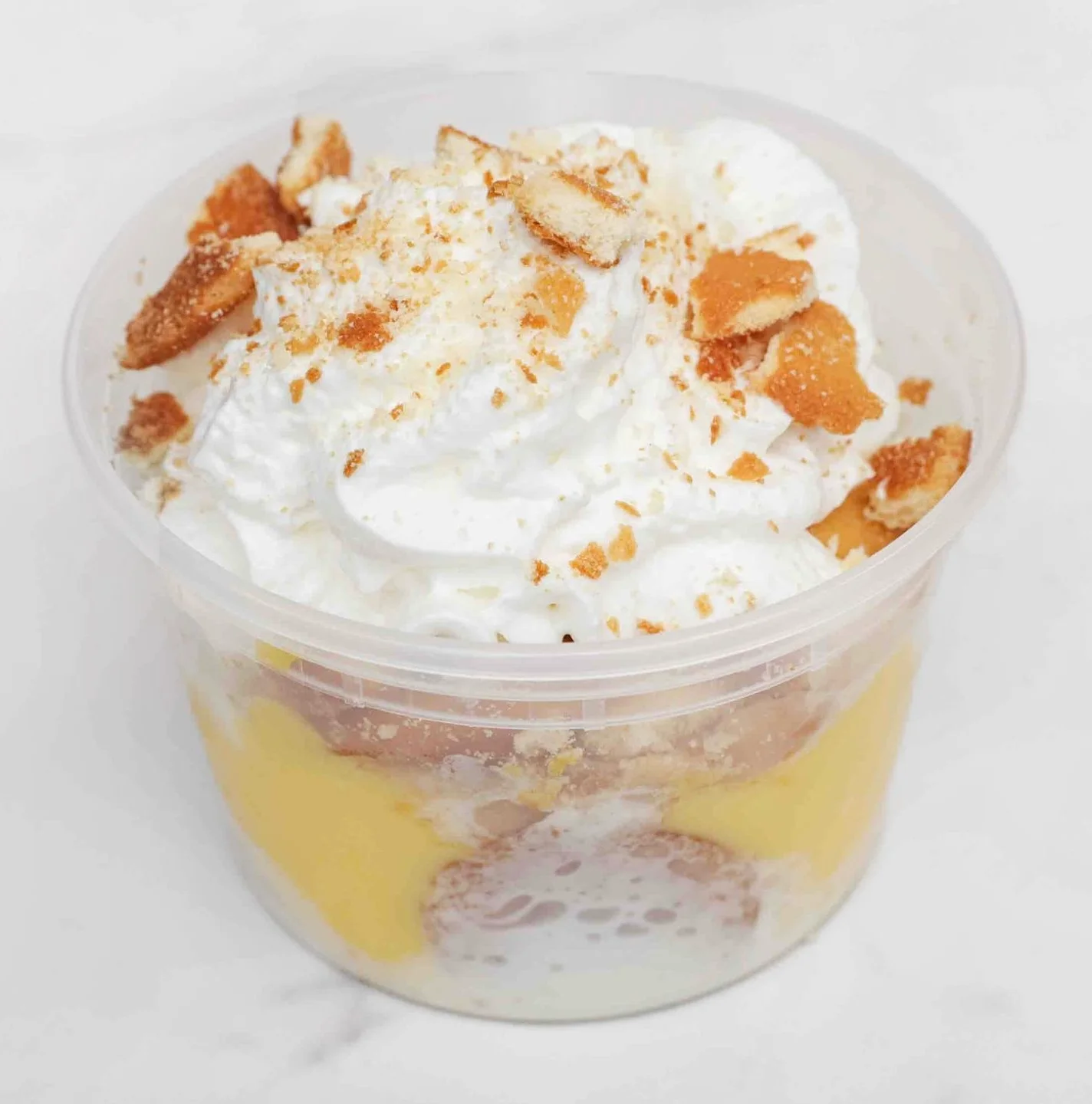 A creamy dessert cup topped with whipped cream and crushed cookies, highlighting a sweet treat.