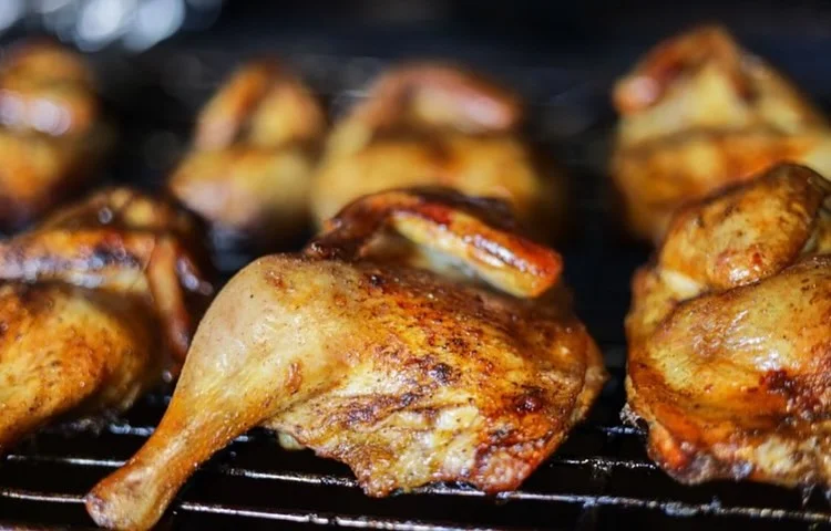 Grilled chicken pieces with a crispy finish, arranged on a barbecue grill.