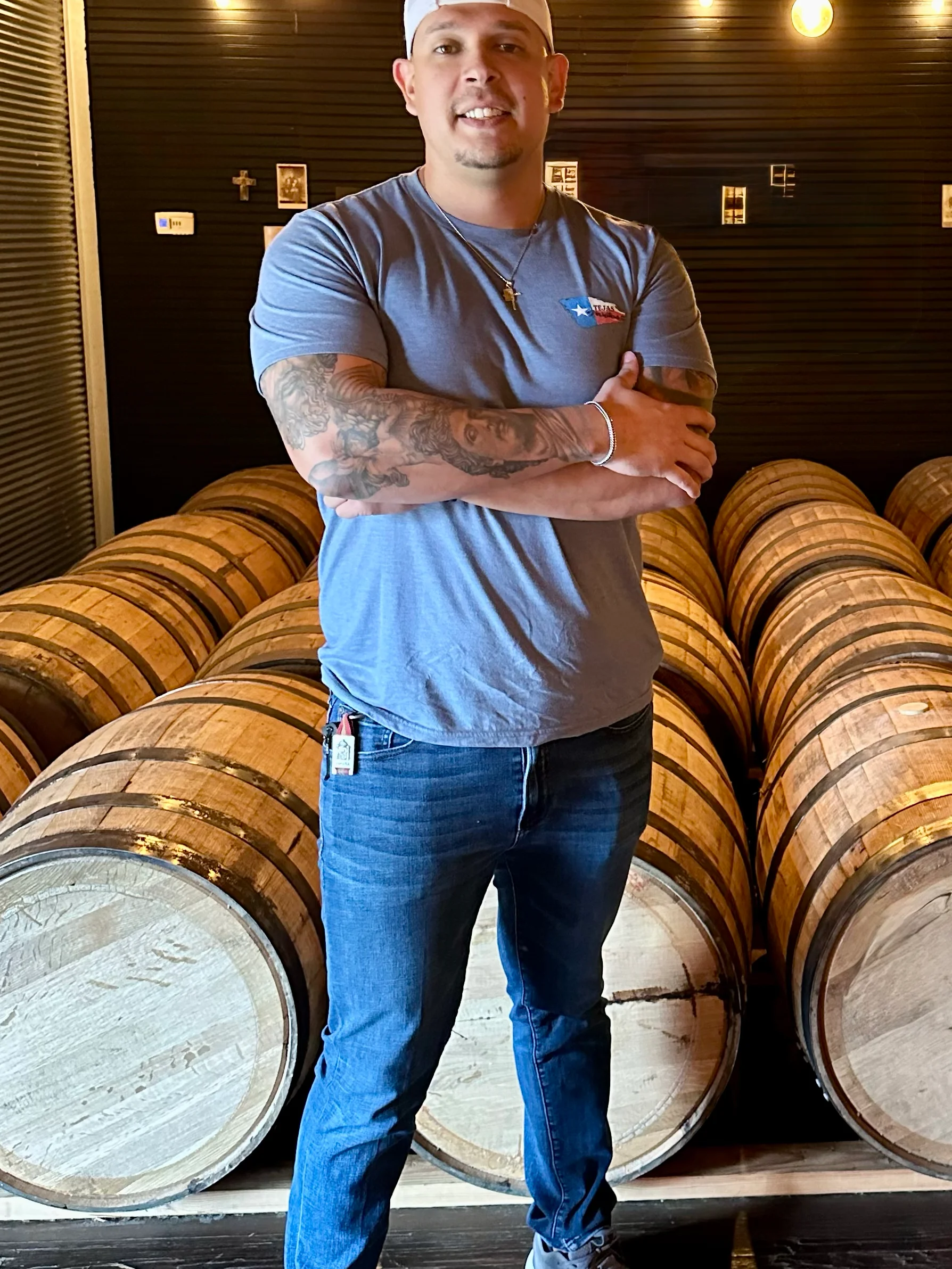 Person standing in a distillery with wooden barrels