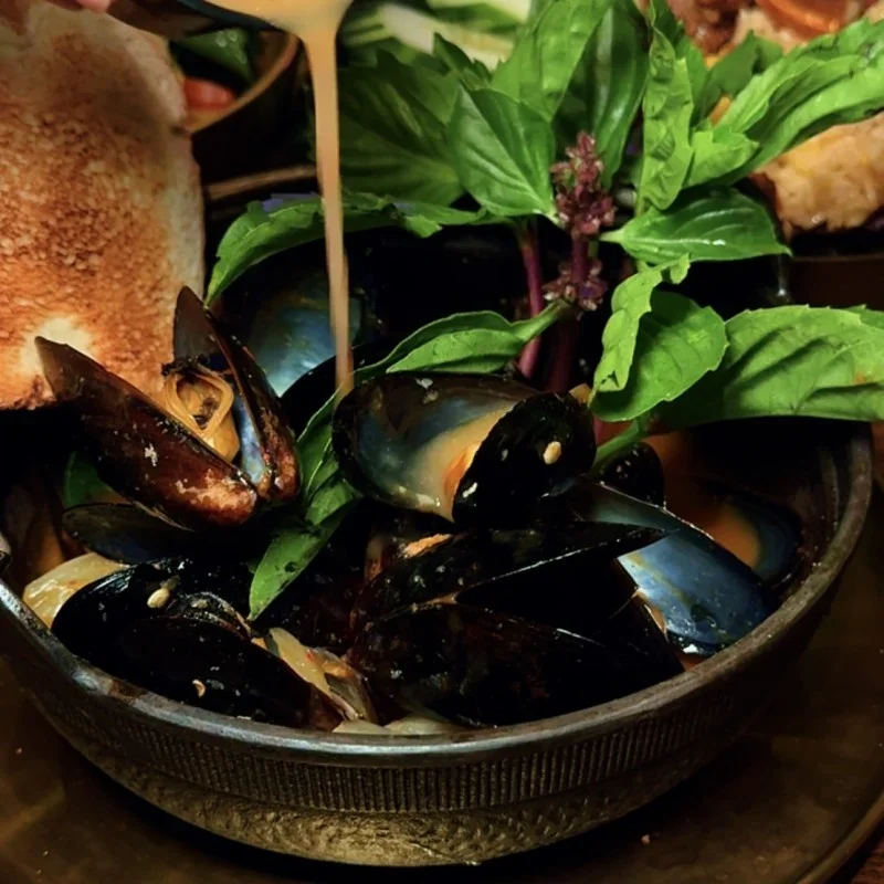 Mussels in a flavorful broth with fresh basil, served with toasted bread
