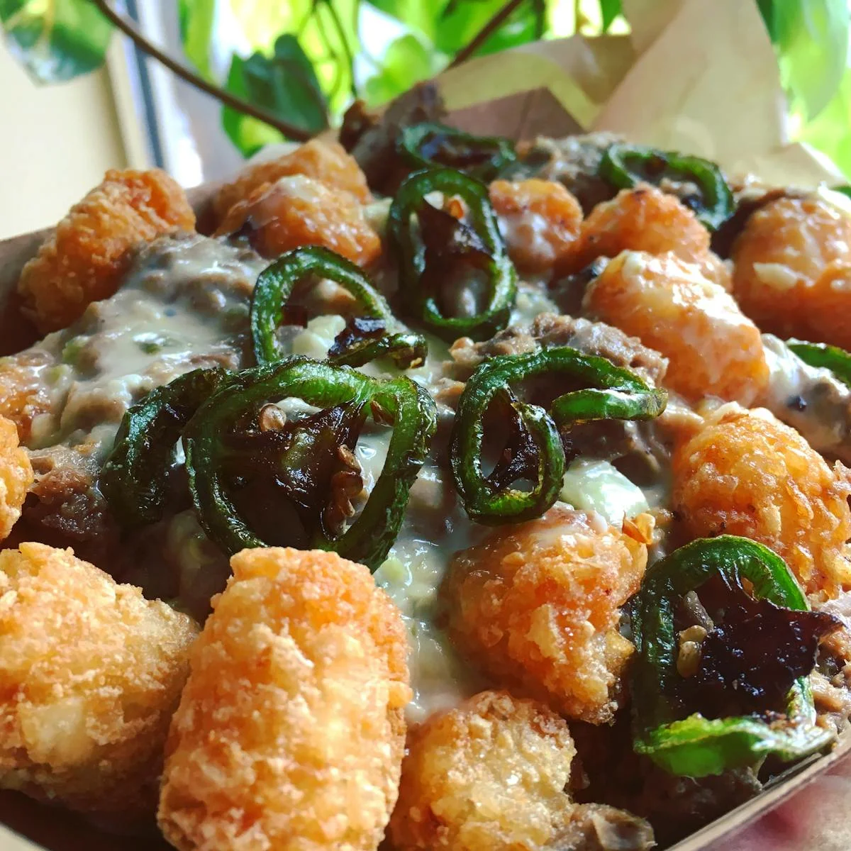 Loaded tater tots with jalapeños and creamy sauce