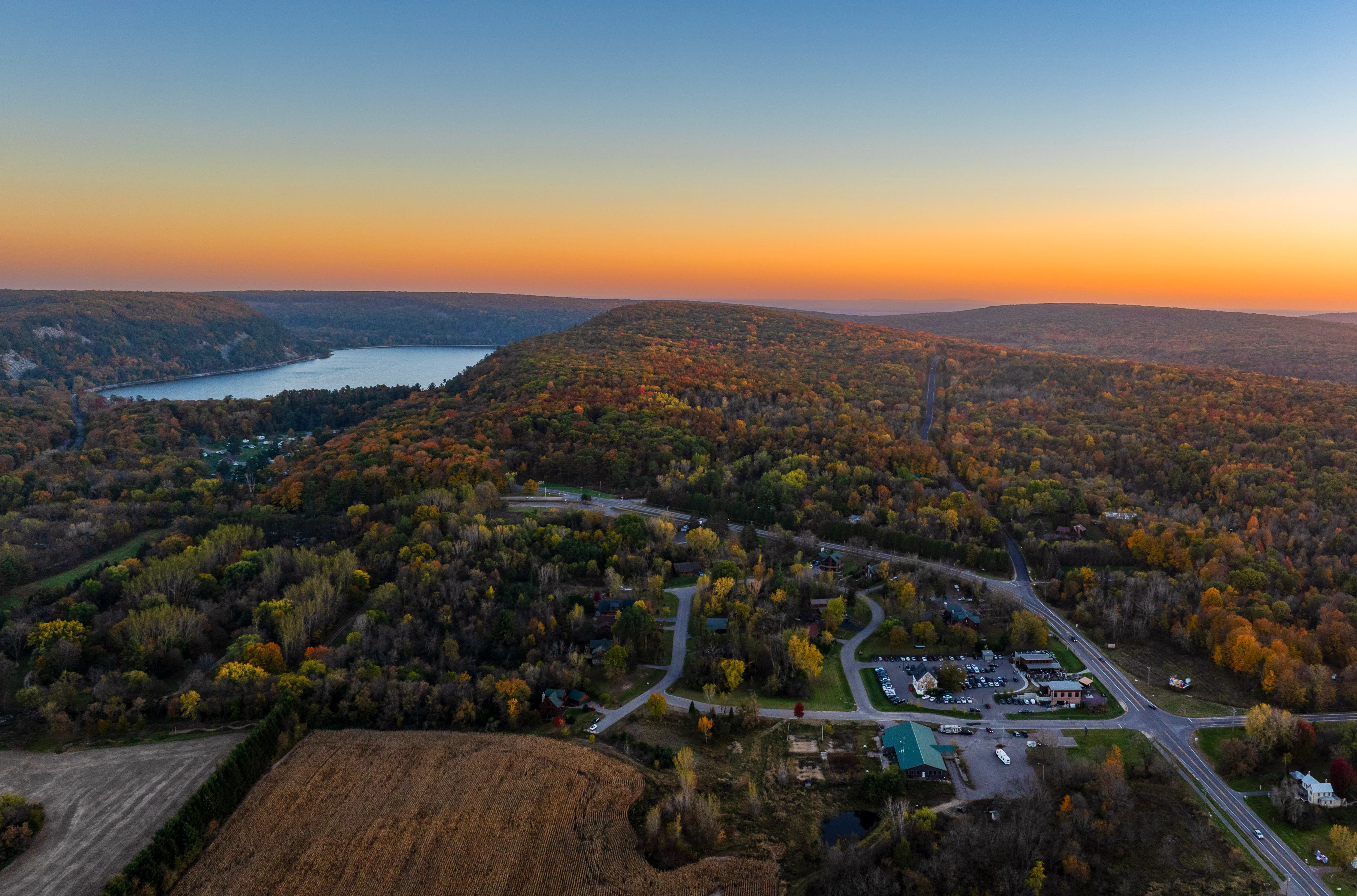 Aerial view of a colorful autumn landscape with a lake and hills.